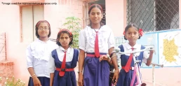 Four smiling girls in school uniforms, representing the importance of girl child education and empowerment.