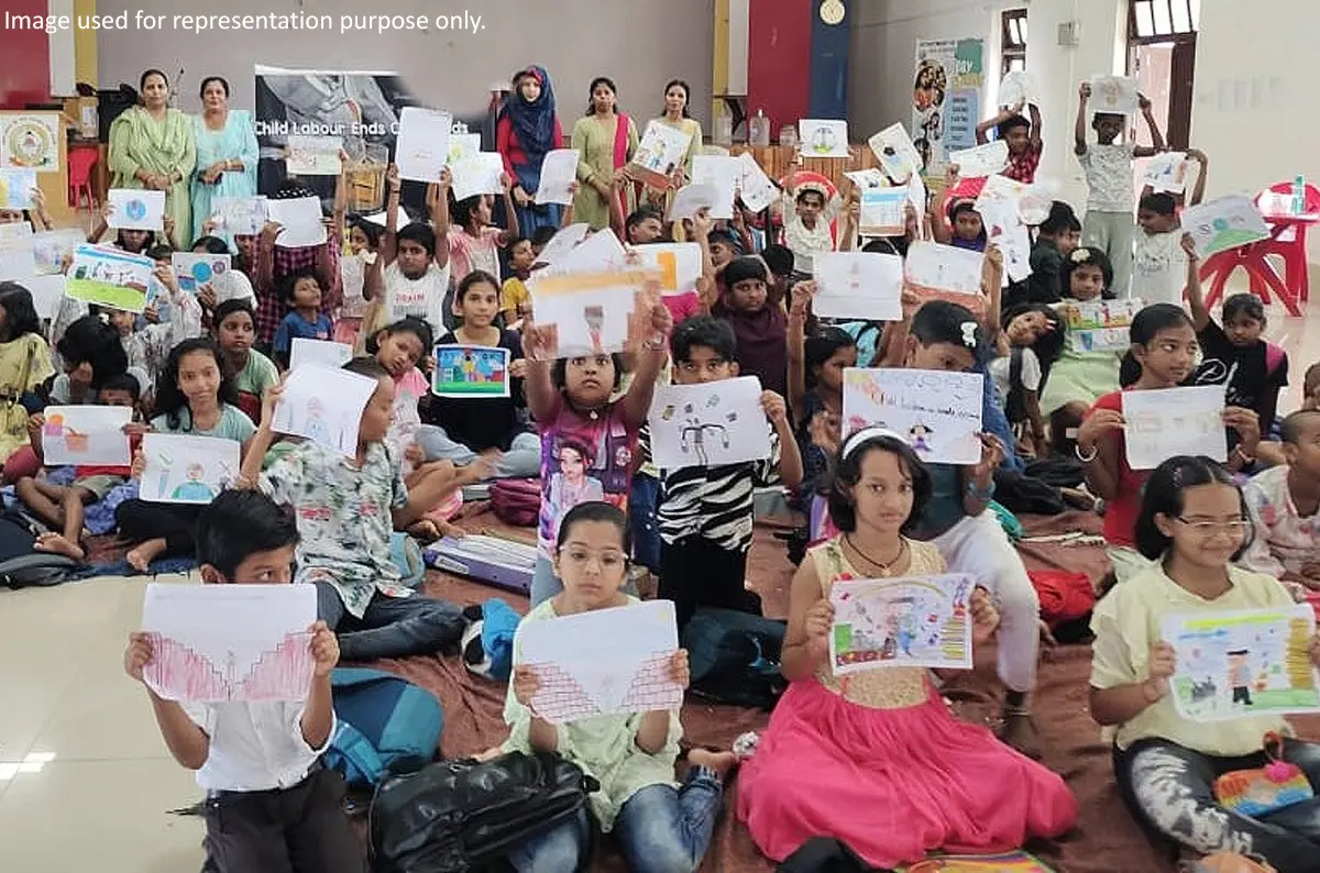 Children proudly displaying their drawings during an educational awareness program promoting child rights and education.