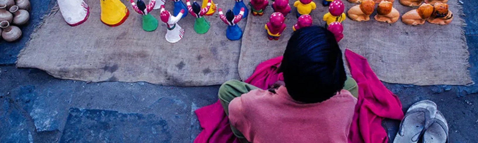 A child sitting beside handmade crafts, highlighting child labor and the need for education and freedom.