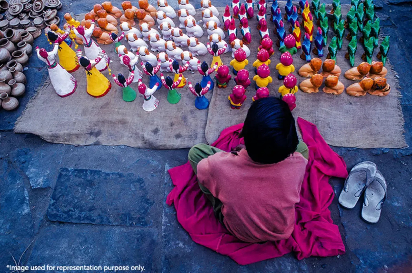 A child sitting beside handmade crafts, highlighting child labor and the need for education and freedom.