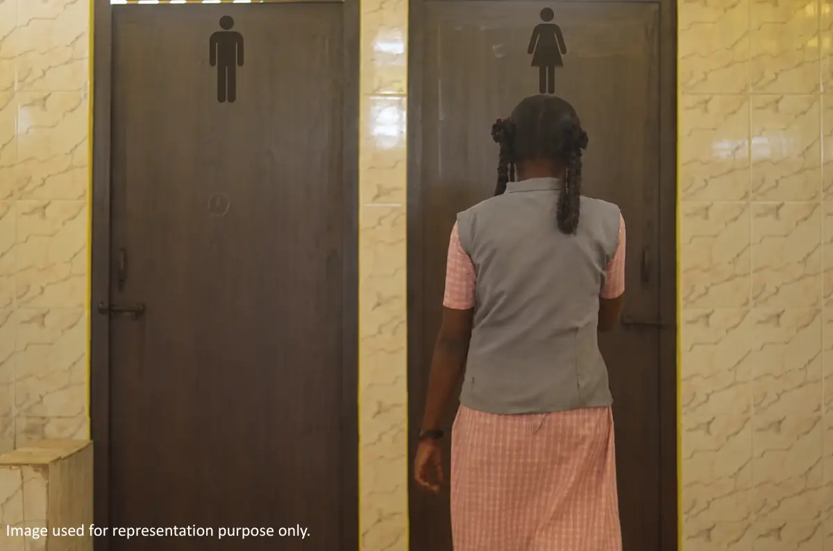 Girl standing outside a clean school washroom supporting WASH initiatives